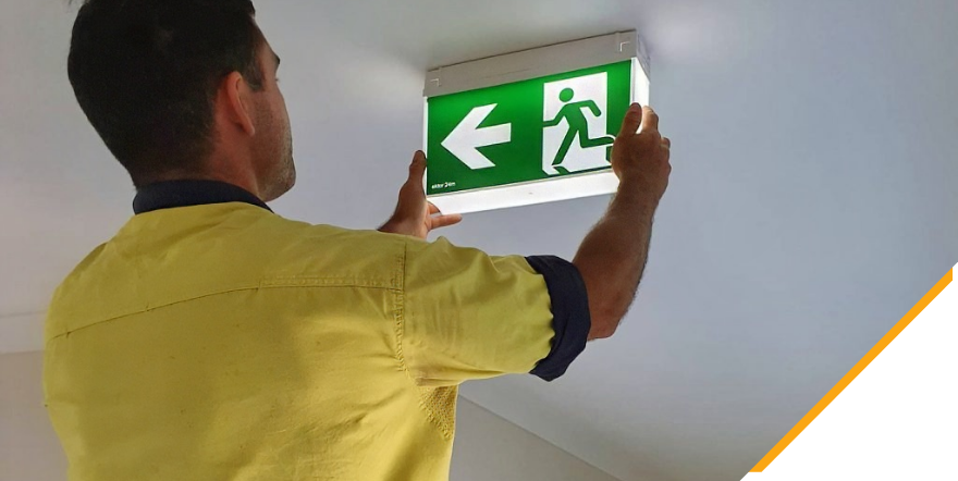 An electrician installing emergency lighting in a commercial building